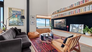 Una sala de estar moderna con un ventanal grande, una estantería, un sofá, una mesa de centro y una chimenea.