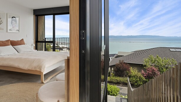 Un dormitorio con una cama grande, vistas al mar y un balcón con baranda de madera.