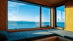Una habitación con un amplio ventanal que ofrece vistas al mar y un puente distante.