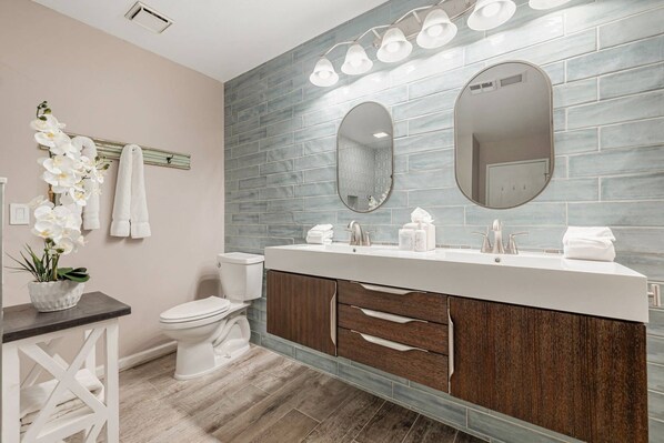 Un baño de diseño moderno, con un espejo grande, un inodoro y un lavabo con armario de madera.