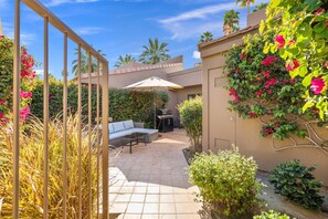 Un espace extérieur aménagé en patio, avec un barbecue, des sièges et un portail.