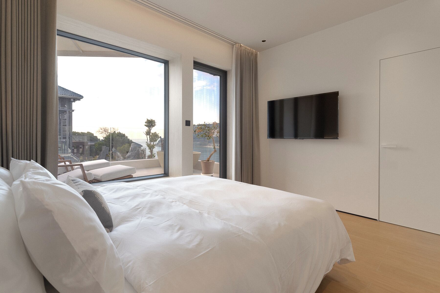 Habitación de hotel moderna con una cama grande, televisión de pantalla plana y balcón con vista a la ciudad.