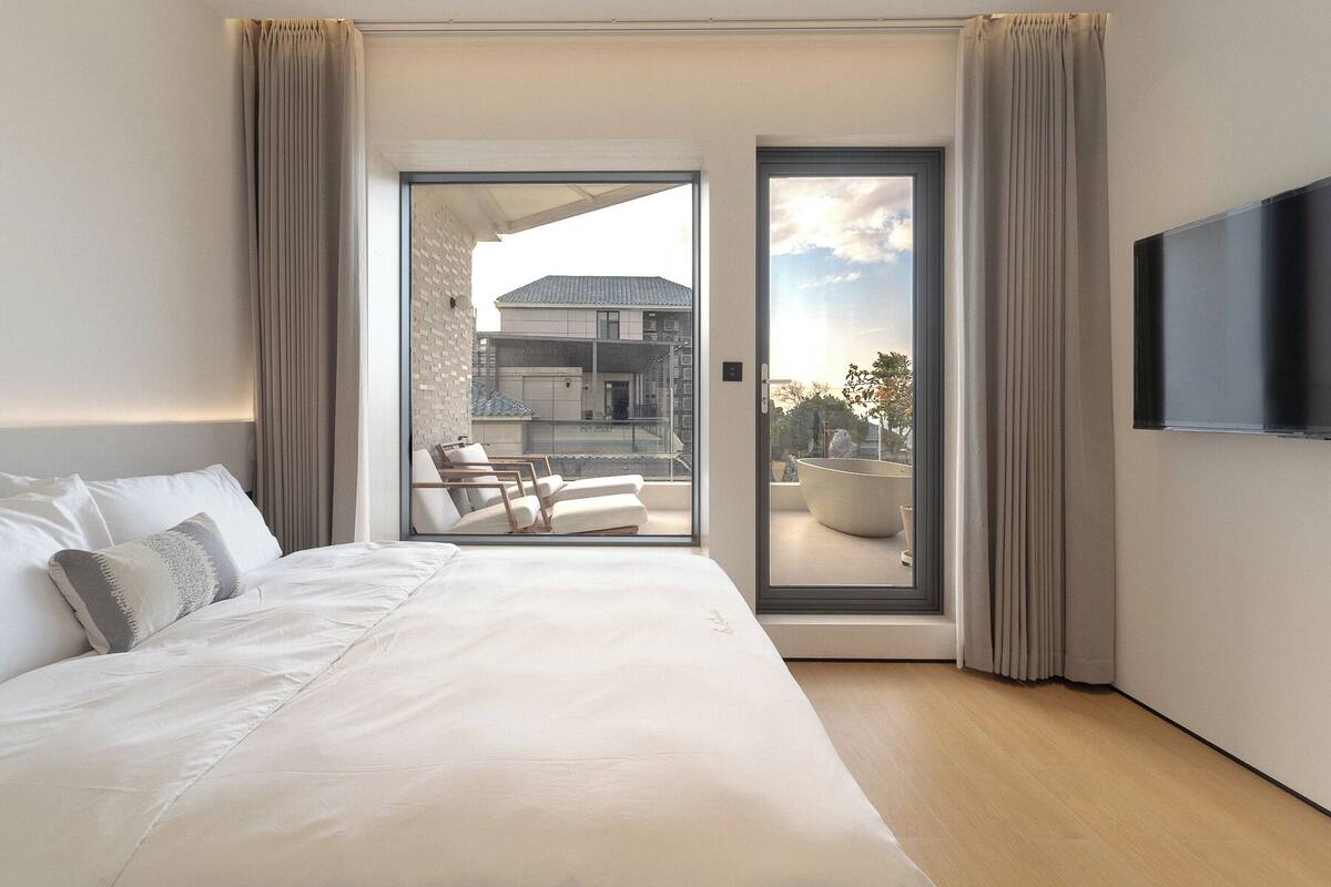 Ett modernt hotellrum med en stor säng, en platt-TV och en balkong med sittmöbler.