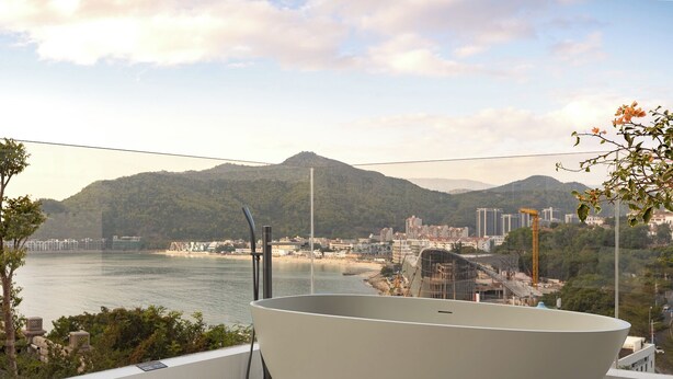 A modern bathroom with a large bathtub, a view of a beach, and a mountainous landscape in the background. - La Felicità (Shenzhen)