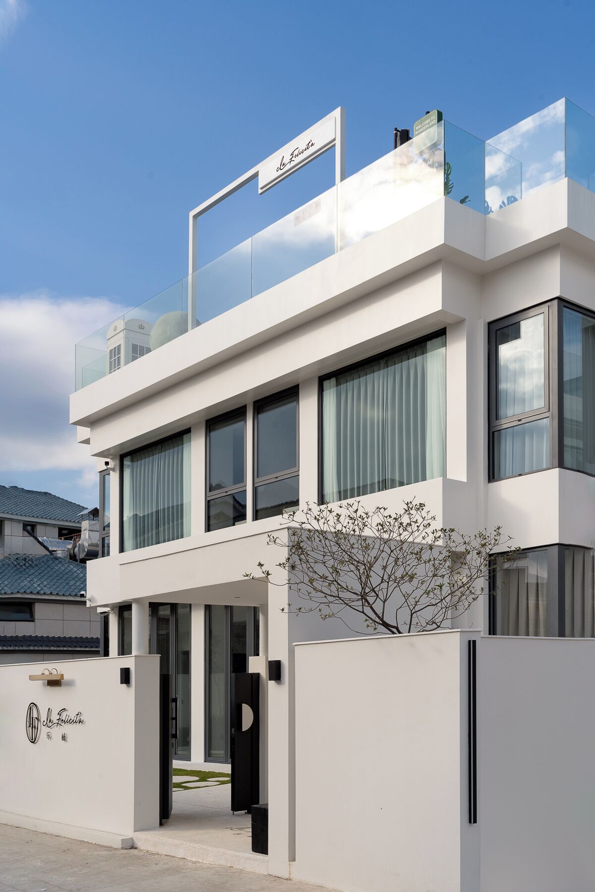 Um edifício moderno de dois andares com teto plano, grandes janelas e uma placa com o nome 