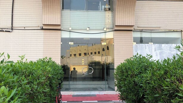A modern building with a glass entrance, a red carpet, and a bicycle parked outside. - Oasis Hostel (Abu Dhabi)