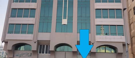 A modern building with a prominent vertical feature and a large arrow pointing downwards.