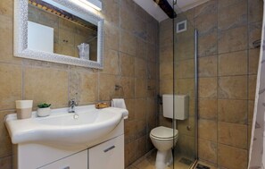 Bathroom features a sink, toilet, and shower area with a glass door.