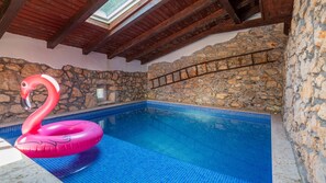Una piscina con pareti in pietra e tetto in legno.