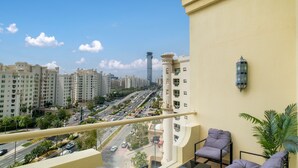 A balcony with a view of a cityscape, including high-rise buildings and a busy road. - LUX The Shoreline Palm Island Suite 2 (Dubai)
