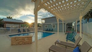 A pool area with lounge chairs and a pergola.