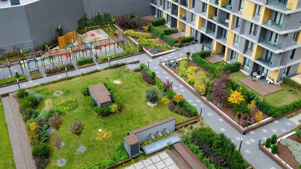 Vista aérea de un complejo residencial con varios edificios de apartamentos, un patio central con áreas verdes y un parque infantil.