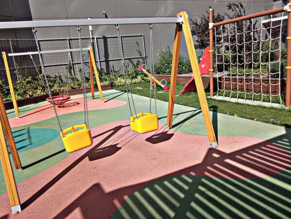 A playground with swings and a netted climbing area. - lUX Residence on High Floor 03 (Istanbul)