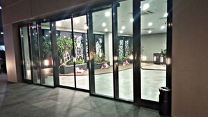Un edificio moderno con grandes puertas de vidrio, piso de baldosas y plantas de interior.