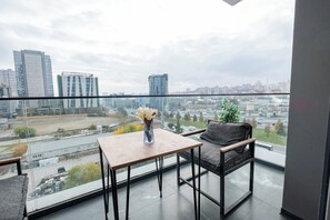 A balcony with a table and chair, a vase with flowers, and a city view. - lUX Residence on High Floor 03 (Istanbul)