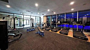 Un gimnasio con cintas de correr, bancos y máquinas de pesas.