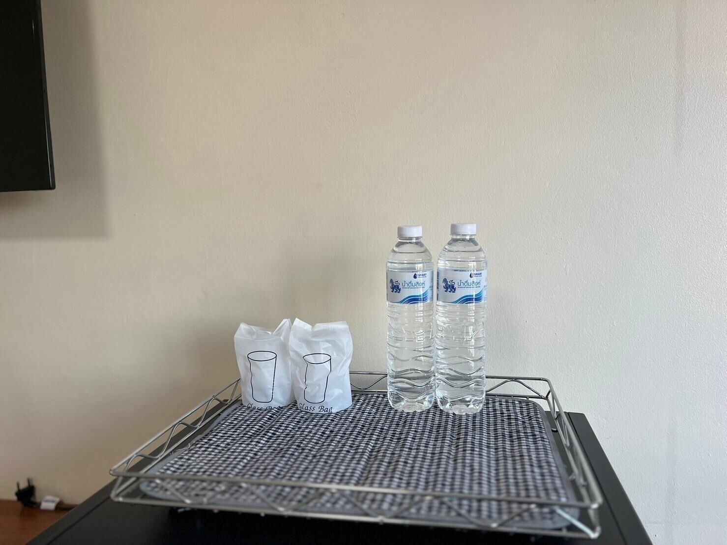 A metal tray with two water bottles and two glass bags on a checkered mat.