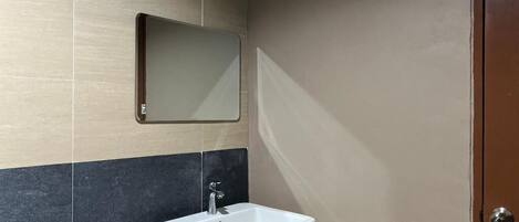 Un baño con un lavamanos blanco, un espejo y una puerta.