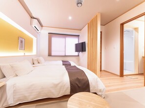 A modern bedroom with a large bed, a TV mounted on the wall, and a sliding door leading to a bathroom. - Hotel Boujosou (Kazuno)