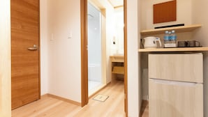 A compact kitchen with a refrigerator, a microwave, and a shelf with bottles and cups. - Hotel Boujosou (Kazuno)