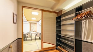 A hotel room with a sliding door leading to a dining area, a shoe rack, and a shelf with hanging clothes. - Hotel Boujosou (Kazuno)