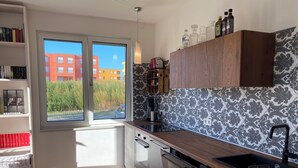 A modern kitchen with a large window, wooden cabinets, and a built-in dishwasher. - Ketzin Havel modern apartment with private garden, close to the water (ketzin)
