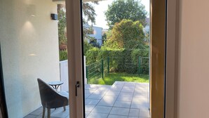 A view from a balcony with a tiled floor, a chair, and a table. - Ketzin Havel modern apartment with private garden, close to the water (ketzin)