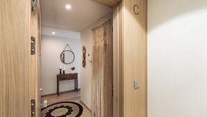 A hallway with a wooden door, a round mirror, a small table with candles, and a patterned rug.