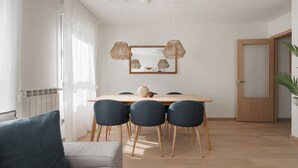 A modern dining area with a wooden table, four chairs, and two hanging rattan lamps.