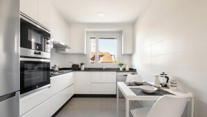 A compact kitchen with white cabinetry, a built-in oven, and a window overlooking a residential area.