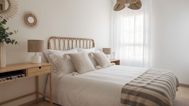 A minimalist bedroom with a bed, bedside tables, lamps, and decorative wall art.