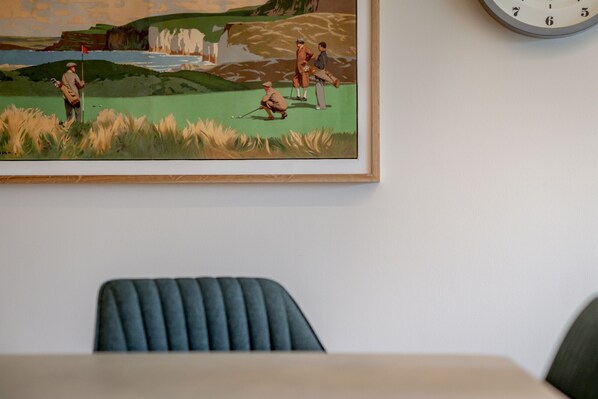 A framed painting of a golf course scene on a wall.