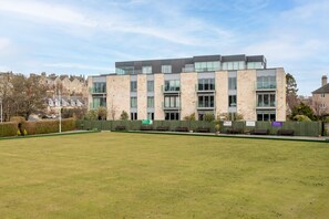 A modern building with a flat roof, large windows, and a grassy courtyard.