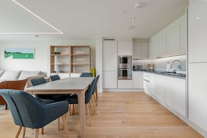 A modern kitchen with white cabinets, a built-in oven, and a microwave.