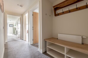 A hallway with a wooden bench, a radiator, and a wooden shelf with hooks.
