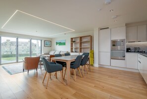 Una cocina moderna con armarios blancos, horno empotrado y microondas.