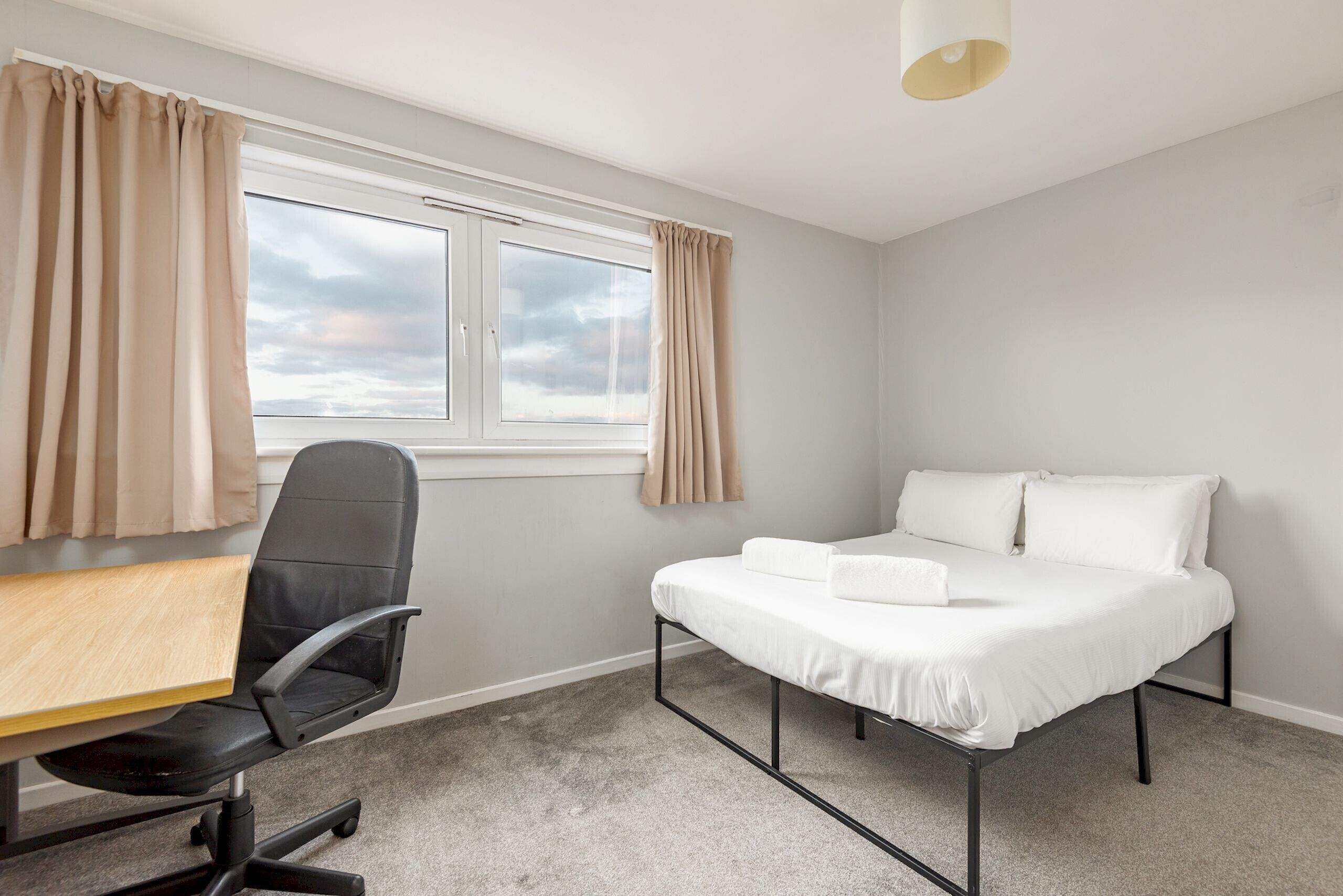 A bedroom with a bed, a desk, and a chair.