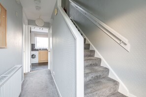 A staircase leading to a laundry area with a view of the kitchen.