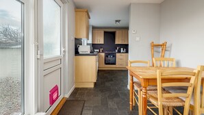 Una cocina pequeña con armarios de madera, una mesa de comedor y sillas.