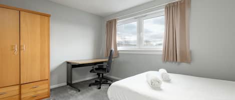 Ein Schlafzimmer mit einem Bett, einem Schreibtisch und einem Kleiderschrank.