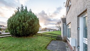 Un edificio residencial con un césped bien cuidado, una cerca de madera y una vista despejada de la calle al fondo.
