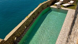 A swimming pool with a stone wall, lounge chairs, and a view of the sea. - Torre Sponda - Torre, Private Beach (Positano)