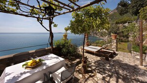 A terrace with a table set for dining, a pergola with a hanging lantern, and a view of the sea. - Torre Sponda - Torre, Private Beach (Positano)