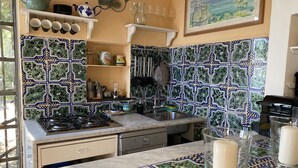 A kitchen with patterned tiles, a gas stove, a sink, and various kitchen utensils. - Torre Sponda - Torre, Private Beach (Positano)