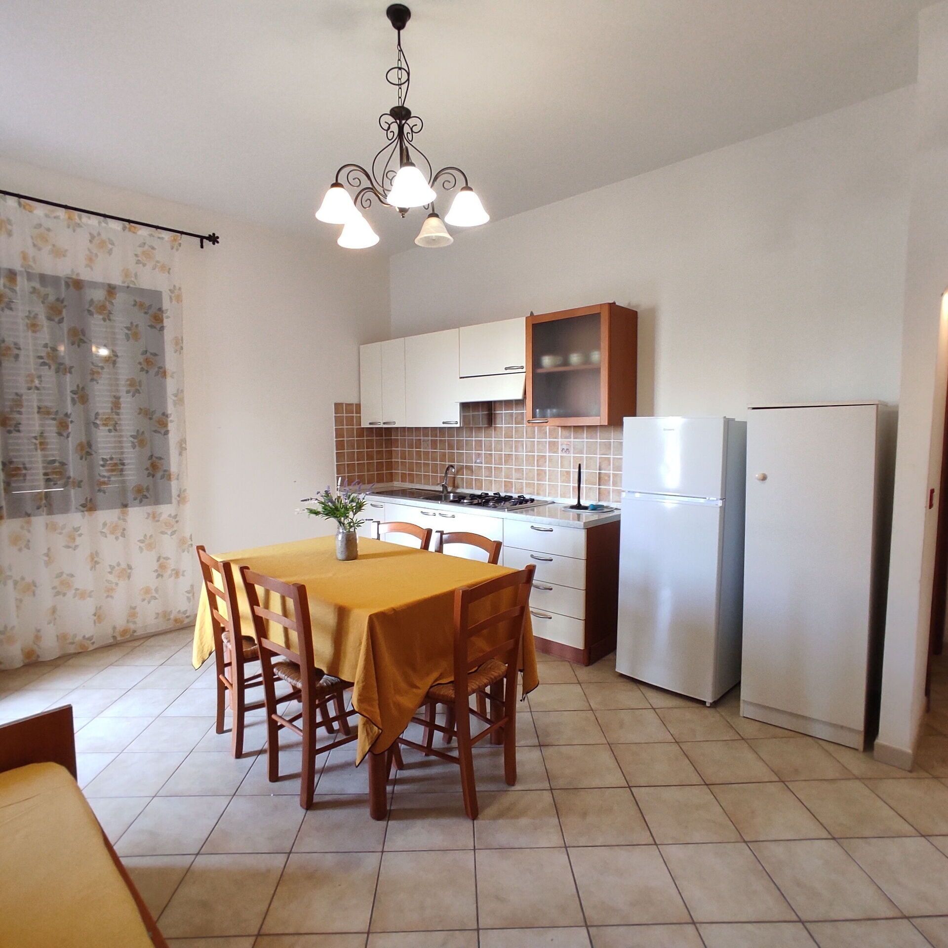 A compact kitchen with a dining table, chairs, a refrigerator, and a stove.