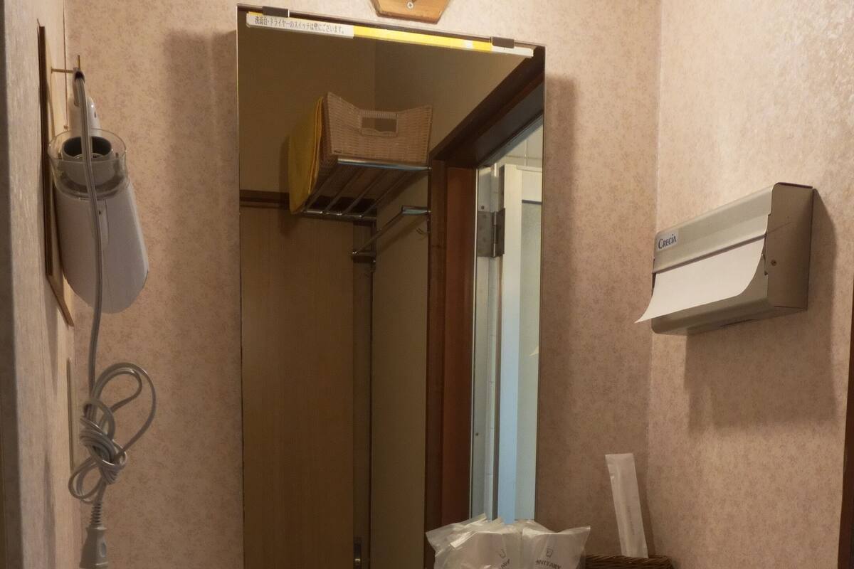 Une salle de bain équipée d’un lavabo, d’un miroir, d’un distributeur de serviettes, d’un distributeur de savon, d’un sèche-mains et d’une étagère contenant des articles de toilette.