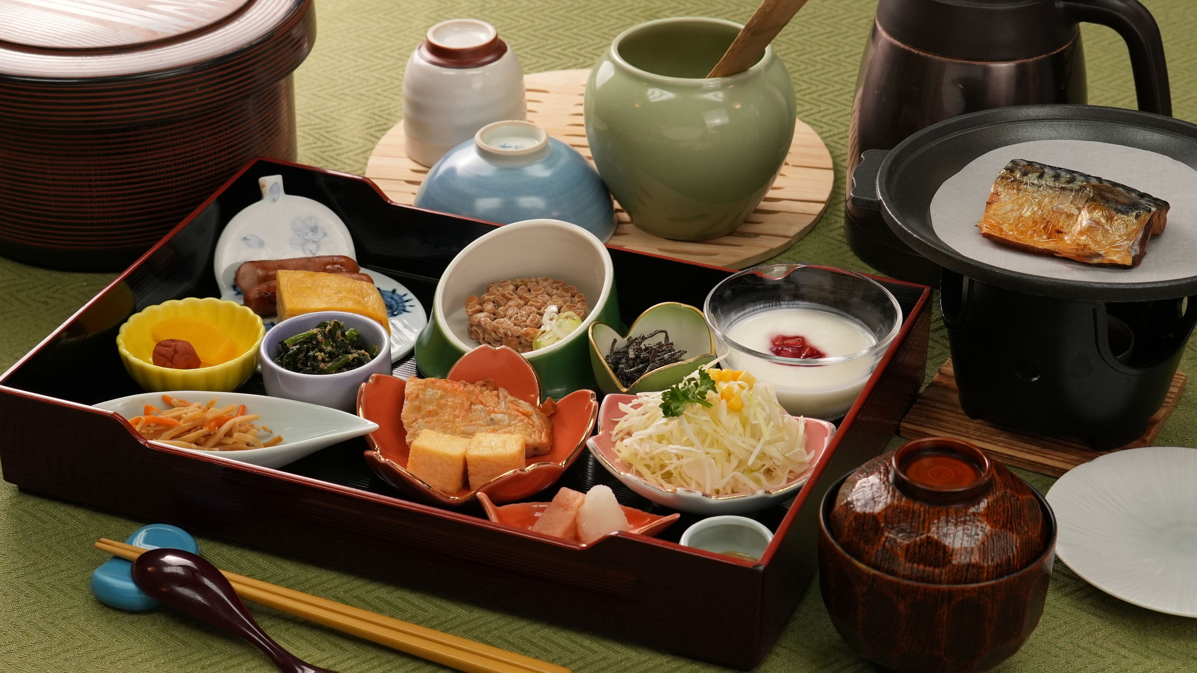A traditional Japanese bento box with various food items and utensils.