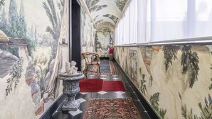 A hallway with a mural, a chair, a vase, and a rug. - Portello Apartment by Geco Vacation Rentals (Genoa)