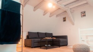 Una sala de estar acogedora con un sofá oscuro, una mesa de centro de madera y un otoman redondo.