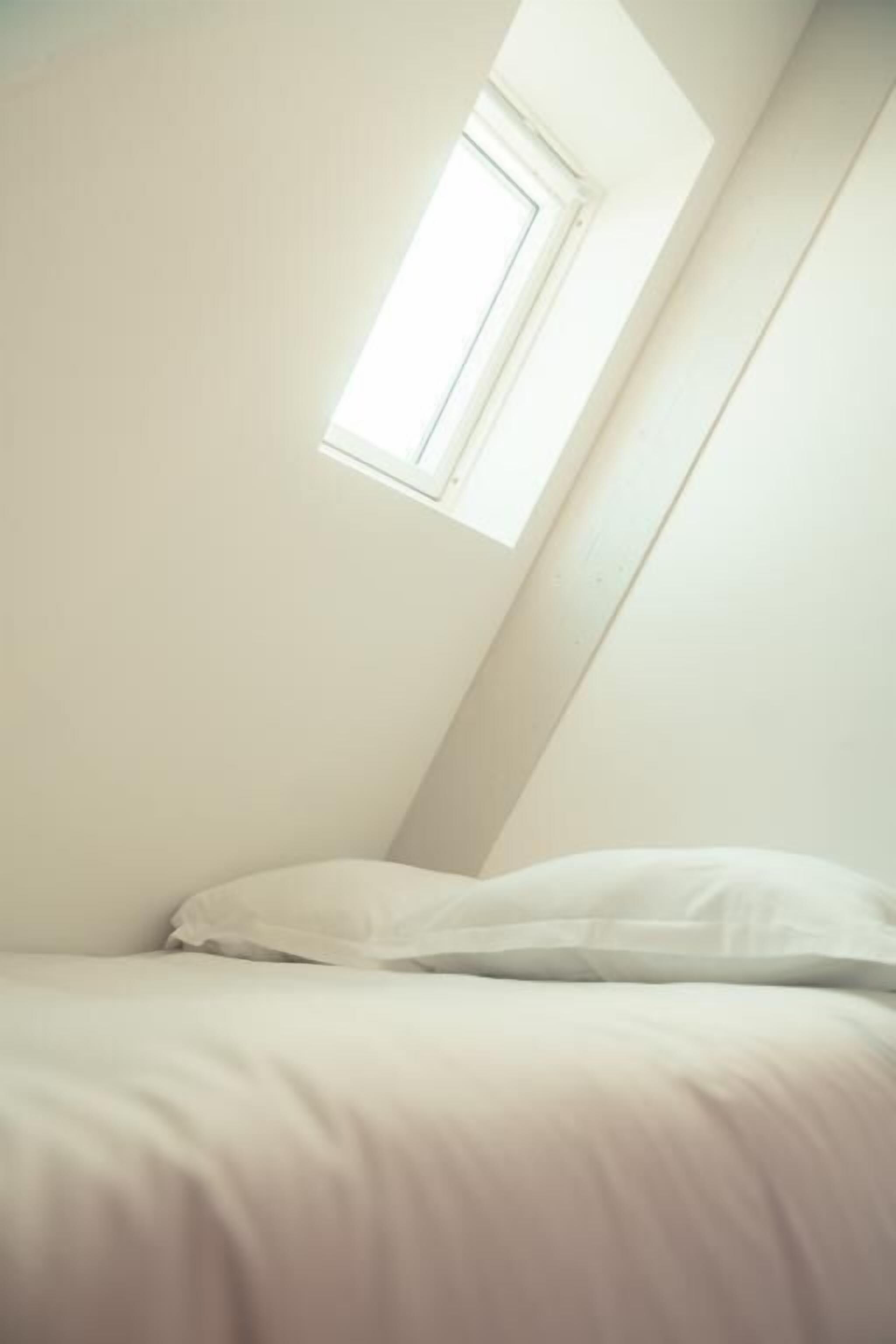 Ein Schlafzimmer mit schrägem Dach und Dachfenster.